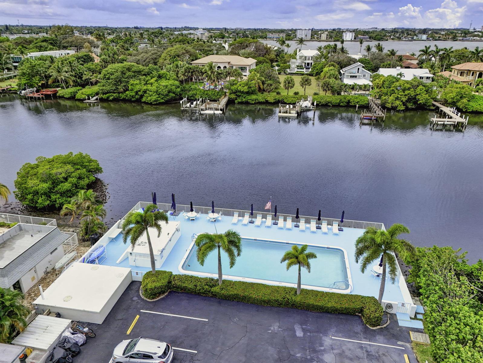 An aerial view shows a swimming pool on a deck overlooking a river with docks — 4001 S Ocean Boulevard # 111, Palm Beach FL 33480, PALM BEACH, FL
