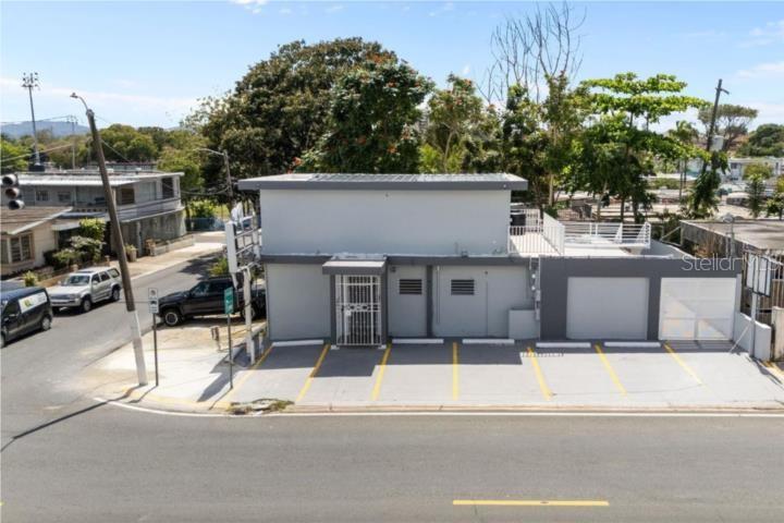 An exterior view of a two-story gray commercial building with a parking lot in front — LAS LOMAS H 22 AVE. SAN PATRICIO, SAN JUAN, PR