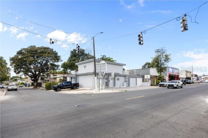 A street-level view shows a grey commercial building at an intersection with traffic lights — LAS LOMAS H 22 AVE. SAN PATRICIO, SAN JUAN, PR