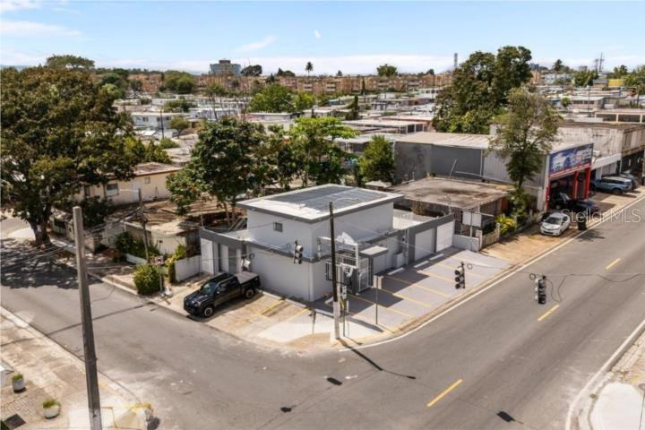 An aerial view shows a small commercial building with solar panels on a corner lot — LAS LOMAS H 22 AVE. SAN PATRICIO, SAN JUAN, PR