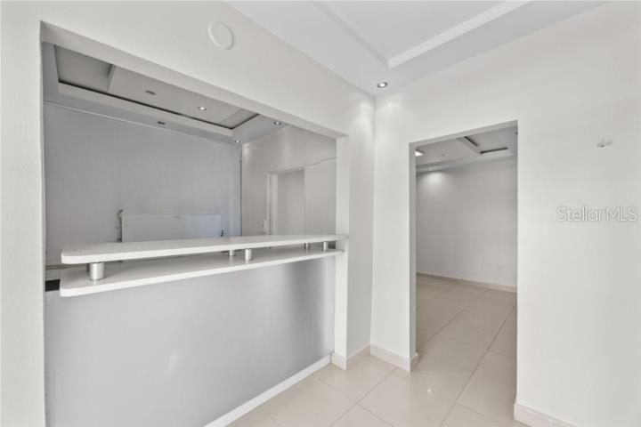 A white interior space features a pass-through bar counter and a doorway to another room — LAS LOMAS H 22 AVE. SAN PATRICIO, SAN JUAN, PR