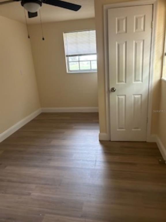 An empty room with light wood-look flooring, a ceiling fan, a window, and a closed door — 26356 ROLLING ACRES DRIVE, BROOKSVILLE, FL