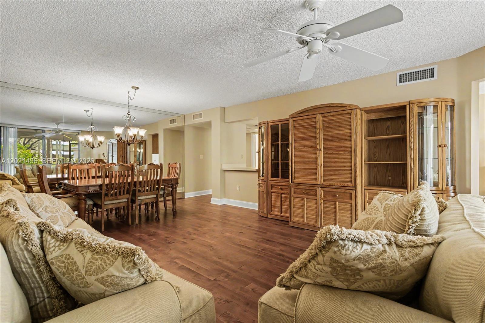 A living and dining room features wood flooring, a ceiling fan, and a large wall unit — 1420 Sheridan St # 3H, Hollywood FL 33020, HOLLYWOOD, FL