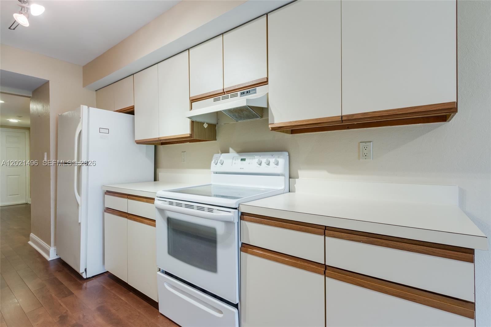 A kitchen features white cabinets with wood trim, white appliances, and light-colored countertops — 1420 Sheridan St # 3H, Hollywood FL 33020, HOLLYWOOD, FL