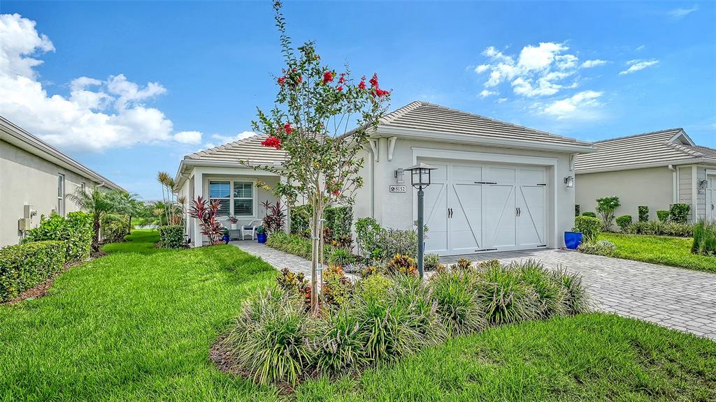 A single-story house with a white garage, a paved driveway, and a landscaped front yard — 8152 STERNWAY ROAD, SARASOTA, FL