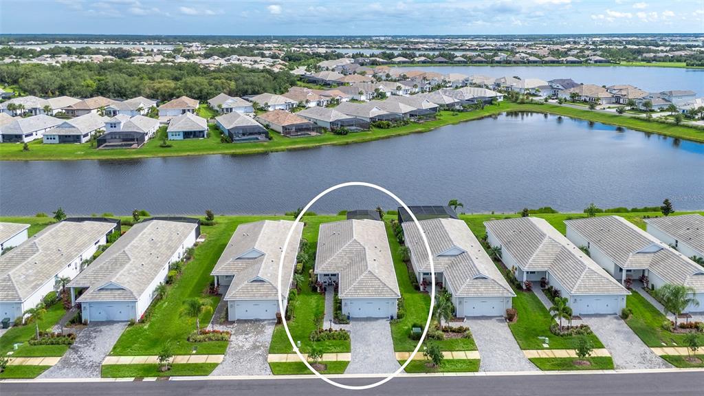 An aerial view shows a row of suburban houses with tiled roofs facing a lake — 8152 STERNWAY ROAD, SARASOTA, FL