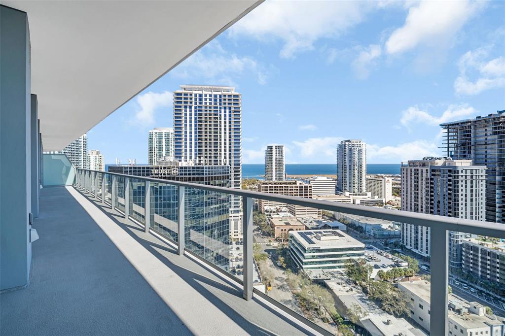 A high-rise balcony overlooks a city skyline with multiple skyscrapers and a distant ocean view — 400 CENTRAL AVENUE UNIT 2205, ST PETERSBURG, FL