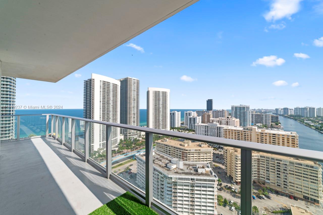 A high-rise balcony with a glass railing overlooks a coastal city and the ocean — 4010 S Ocean Dr # R2409, Hollywood FL 33019, HOLLYWOOD, FL