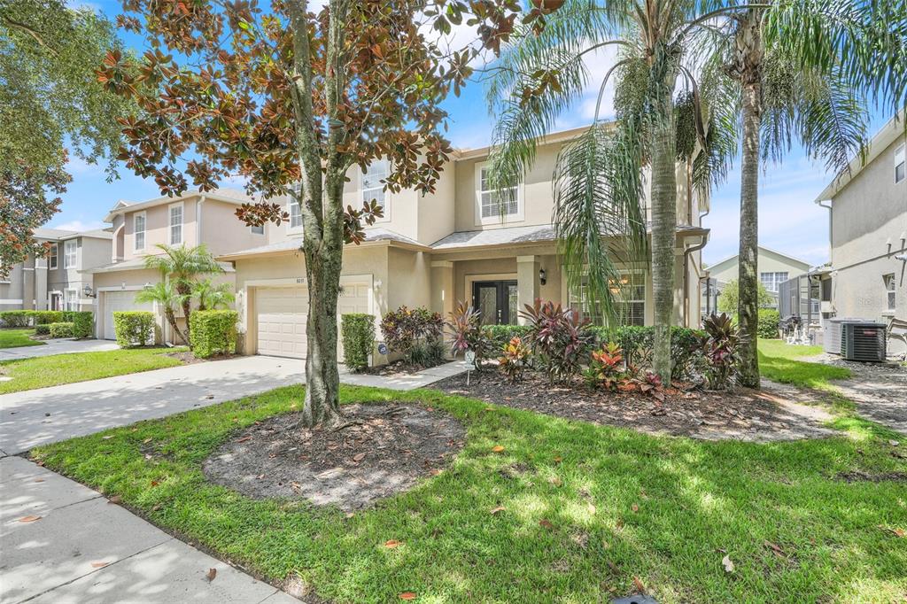 A two-story suburban house with a tan stucco exterior, a garage, and a front lawn — 8033 ACADIA ESTATES COURT, KISSIMMEE, FL