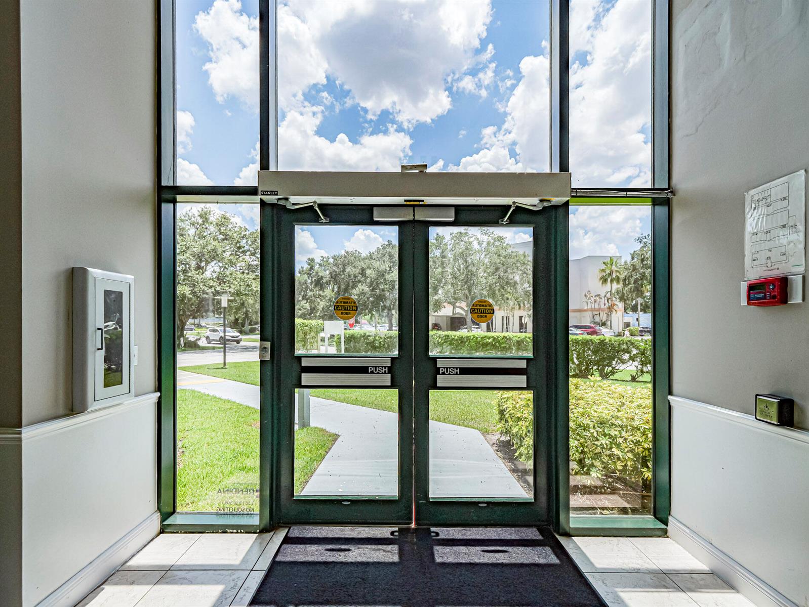 A view through glass double doors showing a sidewalk, green lawn, and trees outside — 3755 7th Terrace # B, Vero Beach FL 32960, VERO BEACH, FL