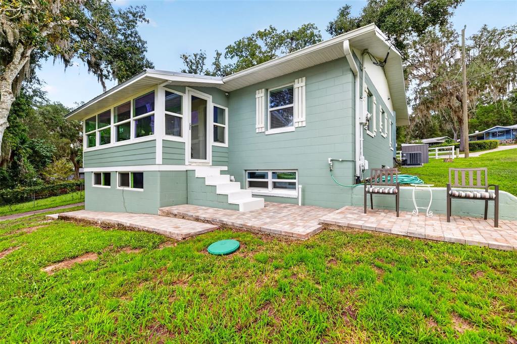 A light green house with a screened porch, white stairs, and a brick patio — 13462 SE 108TH COURT ROAD, OCKLAWAHA, FL