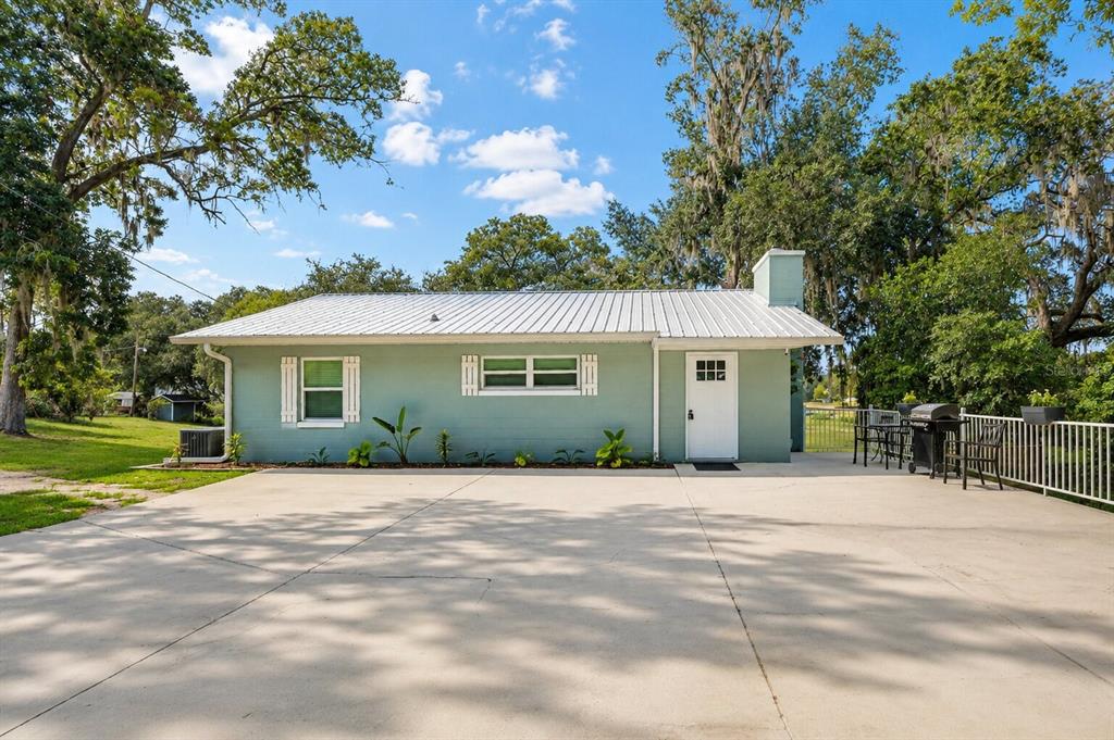 A light green house with a metal roof and a large concrete driveway — 13462 SE 108TH COURT ROAD, OCKLAWAHA, FL