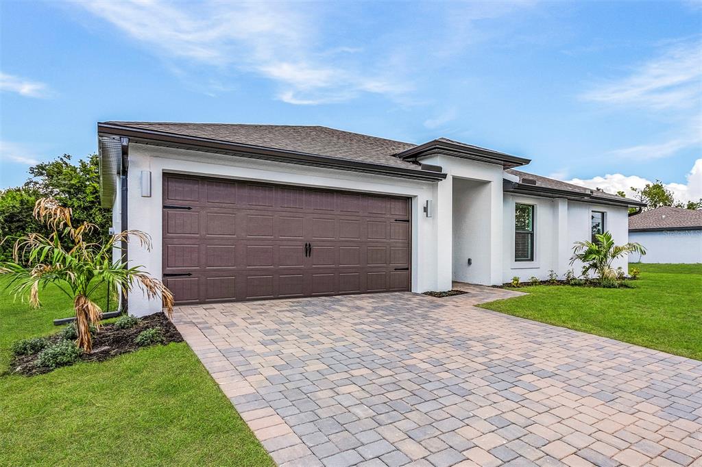 A single-story house with a white stucco exterior, a brown garage door, and a paver driveway — 5952 GILLOT BOULEVARD, PORT CHARLOTTE, FL
