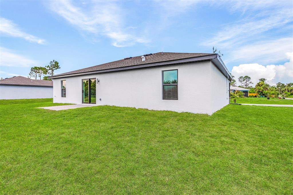 The back exterior of a white house features a sliding glass door and windows — 5952 GILLOT BOULEVARD, PORT CHARLOTTE, FL