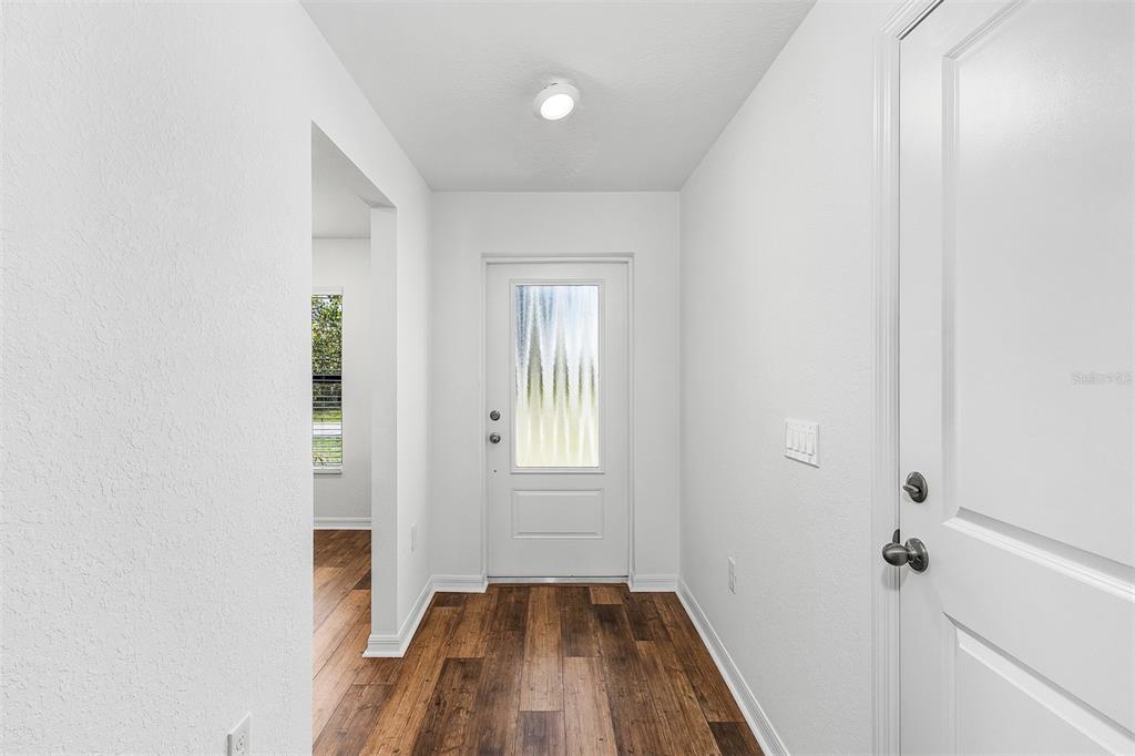 A bright entryway features white walls, a front door with a glass insert, and wood flooring — 5952 GILLOT BOULEVARD, PORT CHARLOTTE, FL