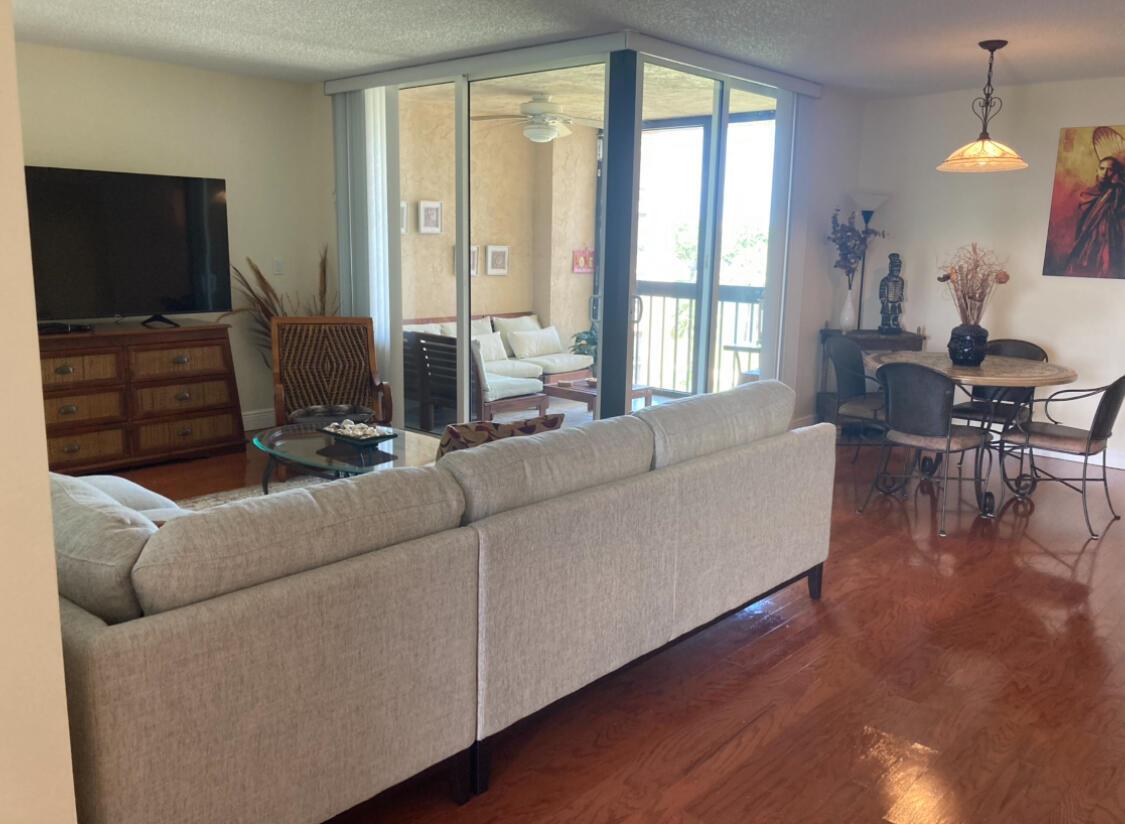 A living and dining area with hardwood floors, a sectional sofa, and a glass-enclosed balcony — 2255 Lindell Boulevard # 4404, Delray Beach FL 33444, DELRAY BEACH, FL