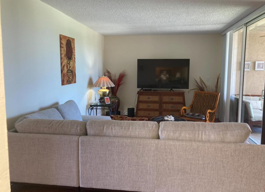 A living room features a large sectional sofa, a television on a dresser, and a chair — 2255 Lindell Boulevard # 4404, Delray Beach FL 33444, DELRAY BEACH, FL