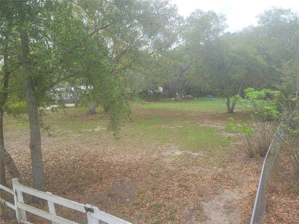 A grassy, tree-filled lot is enclosed by a white fence and a chain-link fence — 11641 BRUIN DRIVE, NEW PORT RICHEY, FL