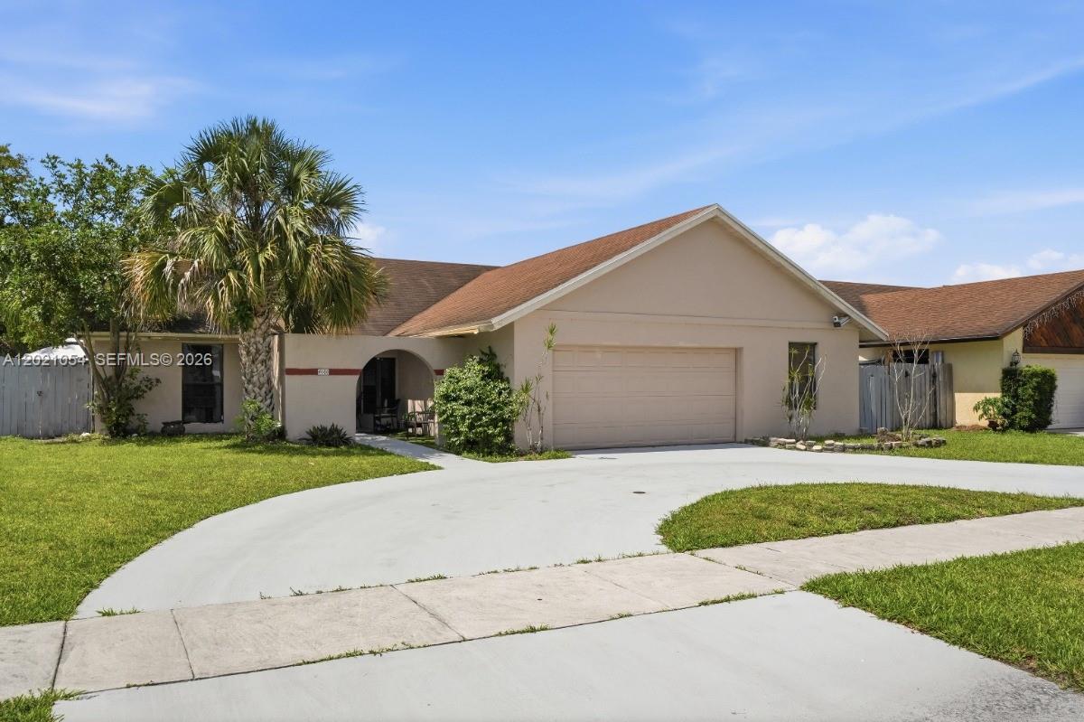 A single-story house with a beige stucco exterior, a brown roof, and a concrete driveway — 4080 NW 1st Pl, Deerfield Beach FL 33442, DEERFIELD BEACH, FL
