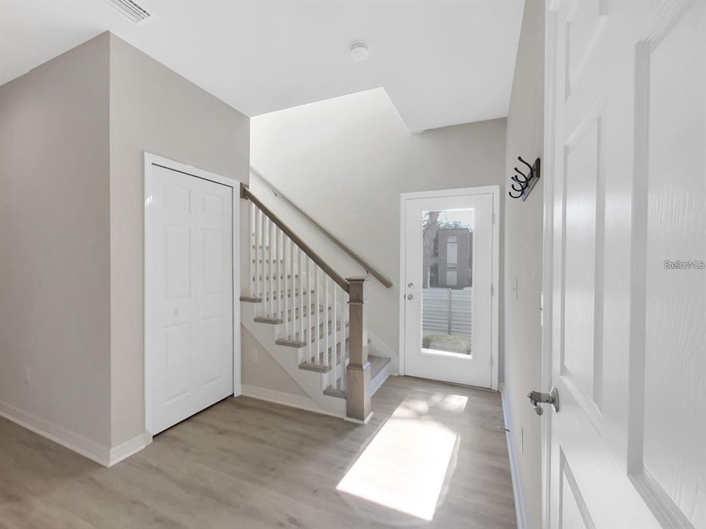 An entryway features light wood-look flooring, a white staircase, and a glass-paneled front door — 8303 KING BLOSSOM COURT, TAMPA, FL