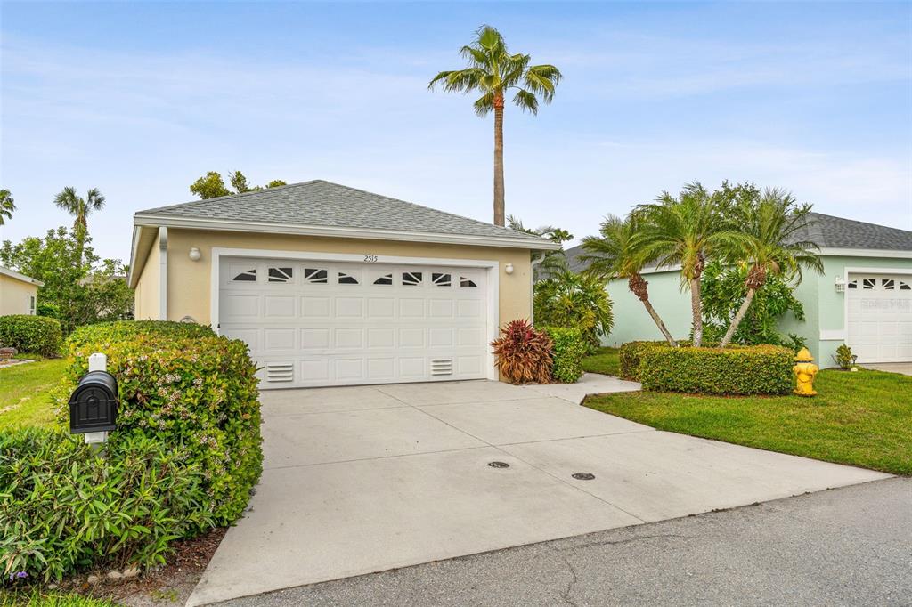 A single-story house with a white two-car garage, a concrete driveway, and palm trees — 2515 LANTANA LANE, PALMETTO, FL