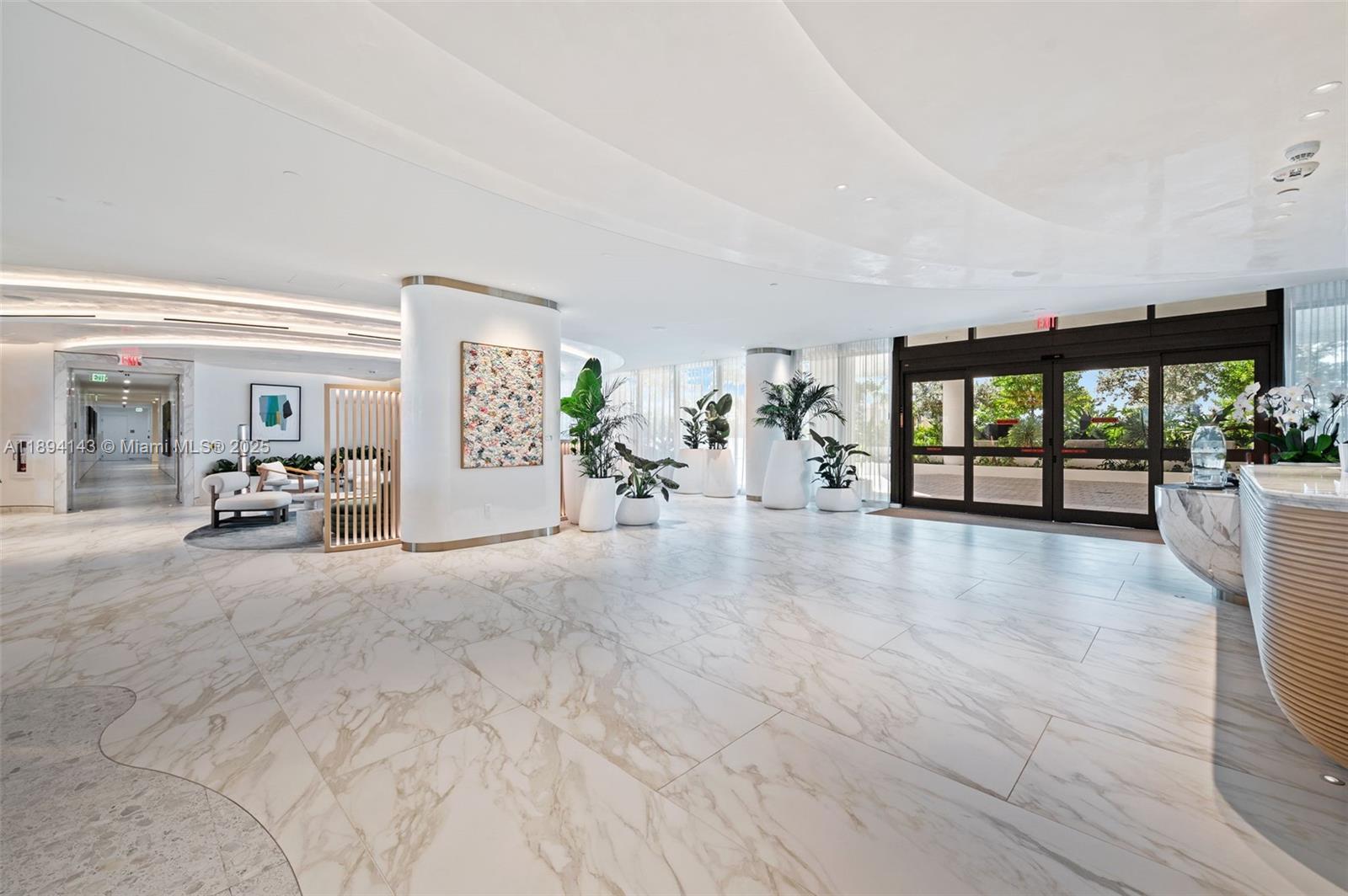 A modern lobby features marble floors, a reception desk, potted plants, and floor-to-ceiling windows — 900 N Ocean Blvd # 1005, Pompano Beach FL 33062, POMPANO BEACH, FL