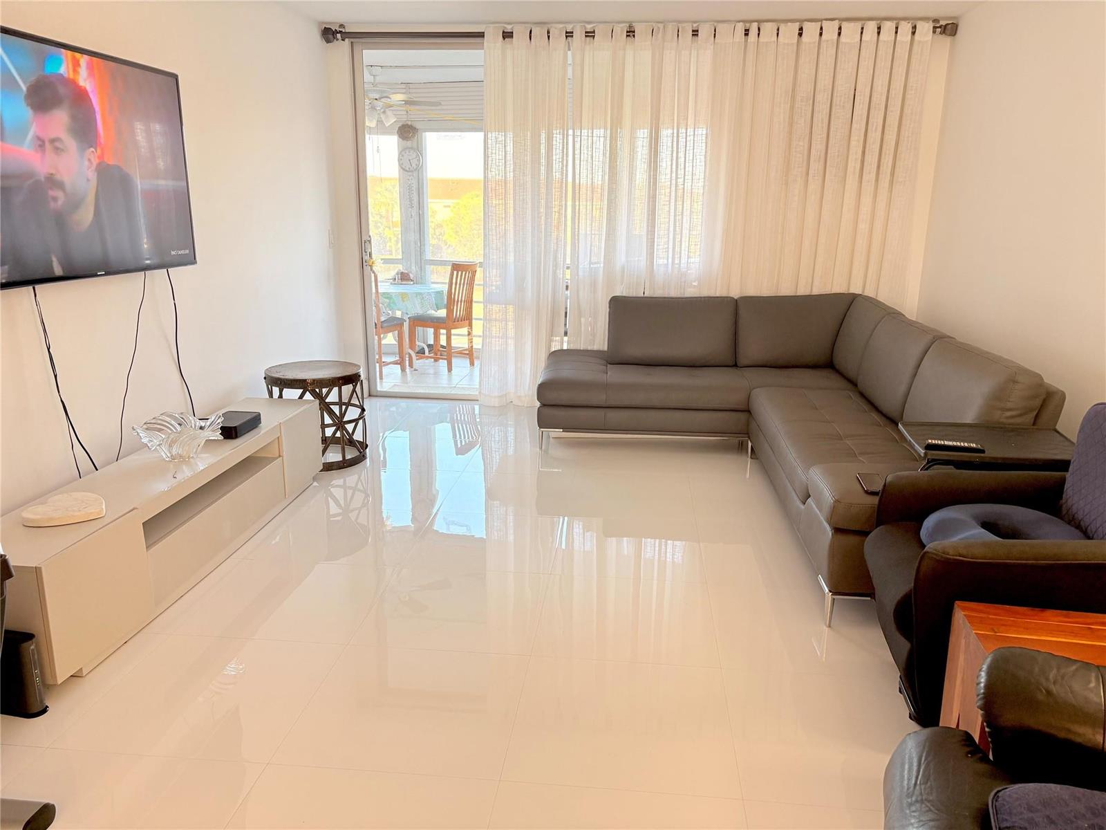 A living room with white tile floors, a grey sectional sofa, and a sliding glass door — 23099 Barwood Lane # 308, Boca Raton FL 33428, BOCA RATON, FL