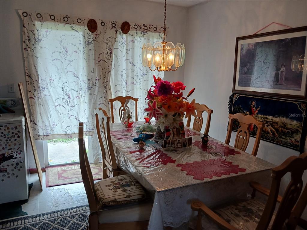 A dining room features a table with a floral centerpiece, wooden chairs, and patterned curtains — 325 ELIZABETH AVENUE, MASCOTTE, FL