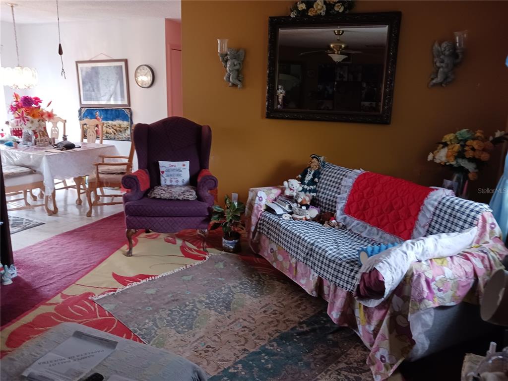 A living room features a purple armchair, a patterned sofa, and a dining area beyond — 325 ELIZABETH AVENUE, MASCOTTE, FL
