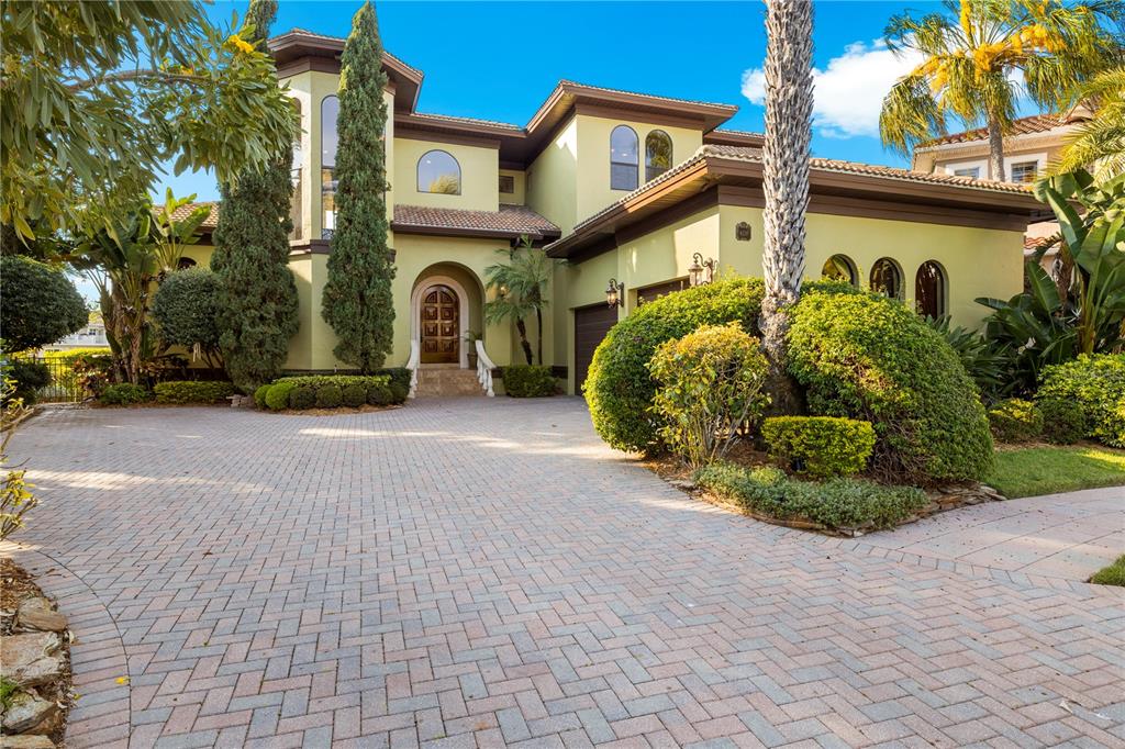 A two-story house with a paved driveway, arched entryway, and lush landscaping — 4128 CAUSEWAY VISTA DRIVE, TAMPA, FL