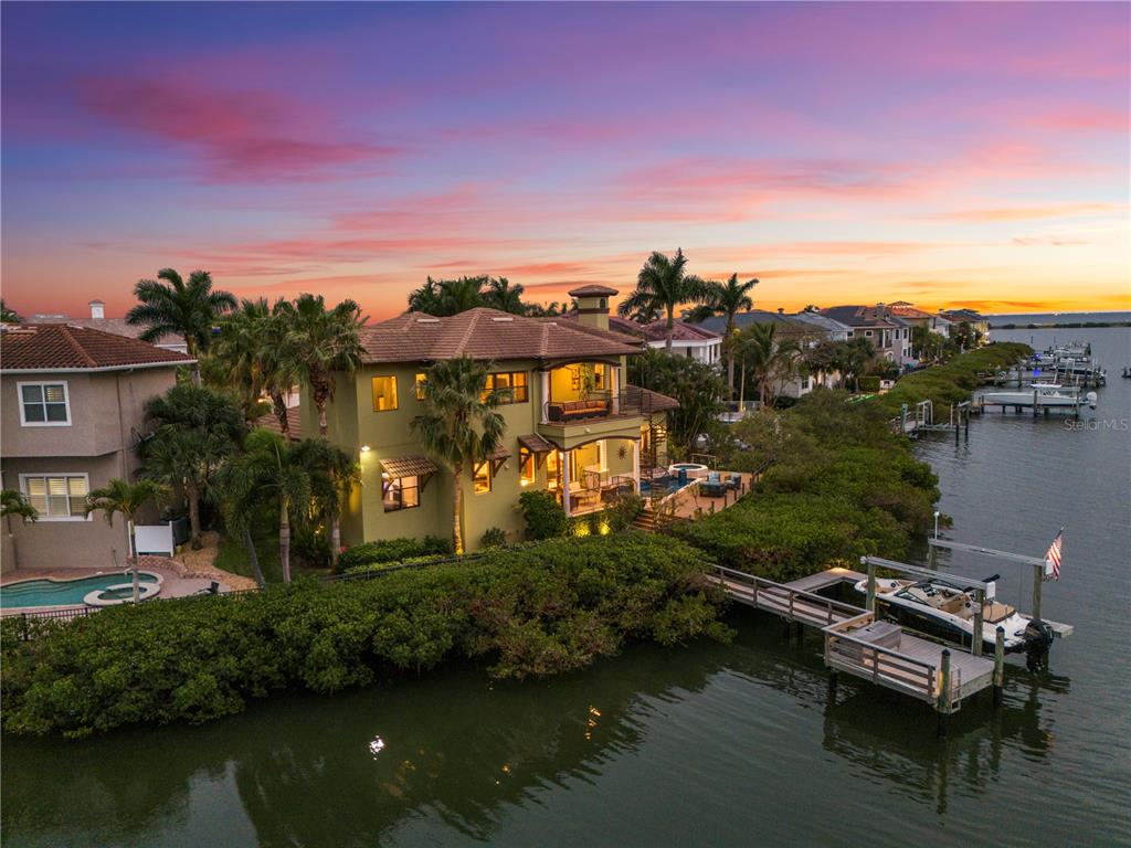 An aerial view of a waterfront house with a private dock and boat at sunset — 4128 CAUSEWAY VISTA DRIVE, TAMPA, FL