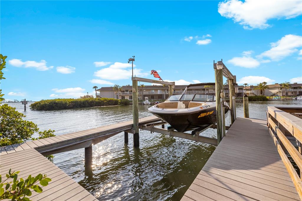 A boat sits on a lift at the end of a wooden dock by water — 4128 CAUSEWAY VISTA DRIVE, TAMPA, FL