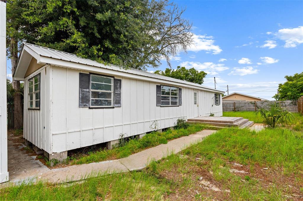 A white mobile home with a metal roof sits on a grassy lot — 21316 SUNSET AVENUE, PANAMA CITY BEACH, FL
