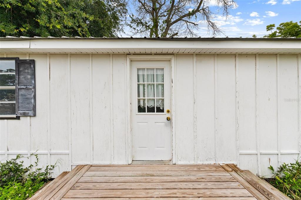 A white exterior wall with a wooden deck and a door with a window — 21316 SUNSET AVENUE, PANAMA CITY BEACH, FL