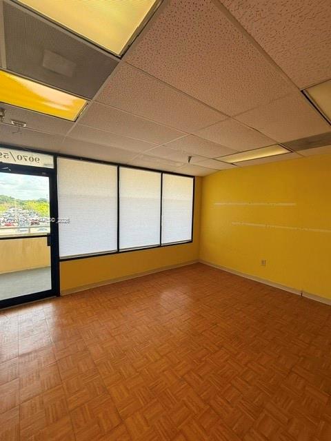 An office space features yellow walls, a parquet wood floor, and a drop ceiling — 9070 Kimberly Blvd # 59, Boca Raton FL 33434, BOCA RATON, FL