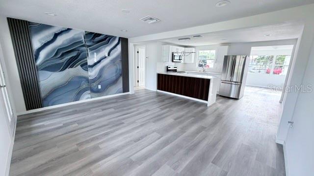 An open-concept kitchen and living area features light wood flooring and a blue agate accent wall — 4607 PIRATE PLACE, NEW PORT RICHEY, FL