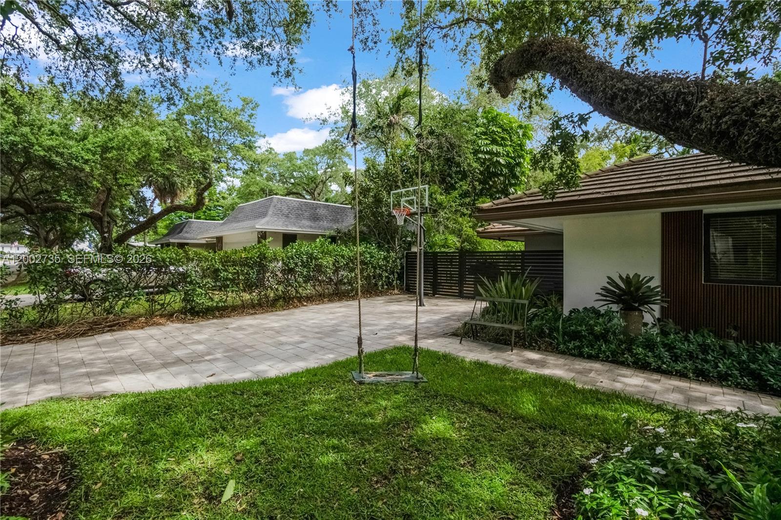 A paved driveway and walkway lead to a house exterior with a hanging rope swing — 2140 NE 190th Ter, Miami FL 33179, MIAMI, FL
