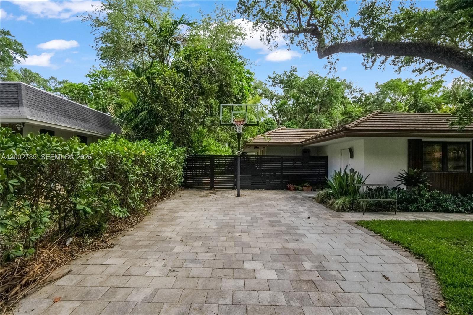 A paved driveway features a basketball hoop in front of a dark wooden privacy fence — 2140 NE 190th Ter, Miami FL 33179, MIAMI, FL