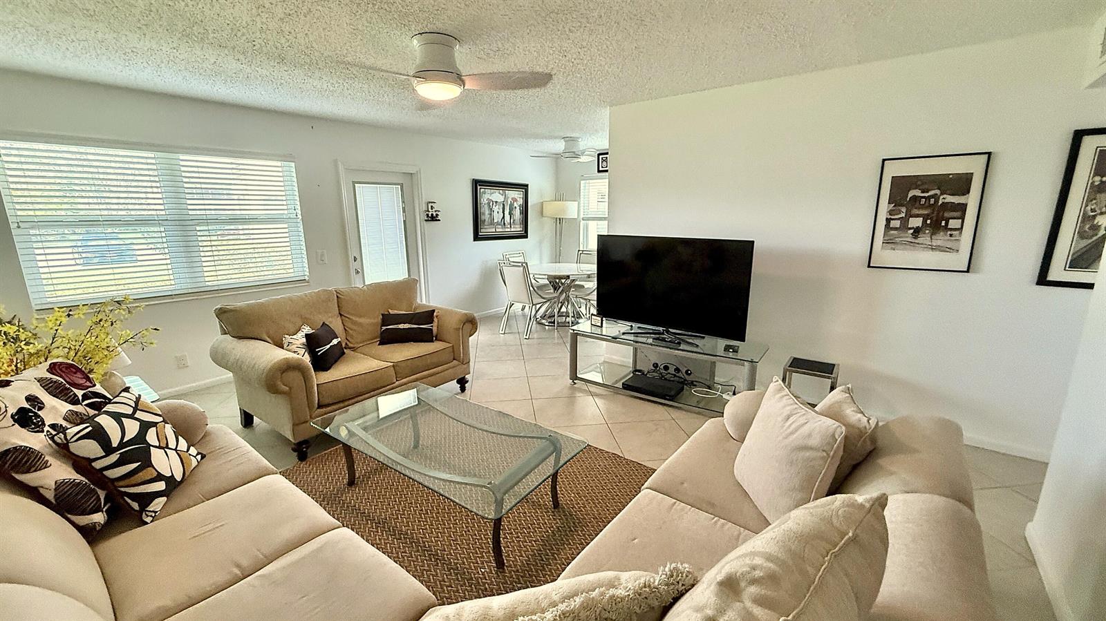 A living room features beige sofas, a glass coffee table, and a television on a stand — 316 Markham, Deerfield Beach FL 33442, DEERFIELD BEACH, FL