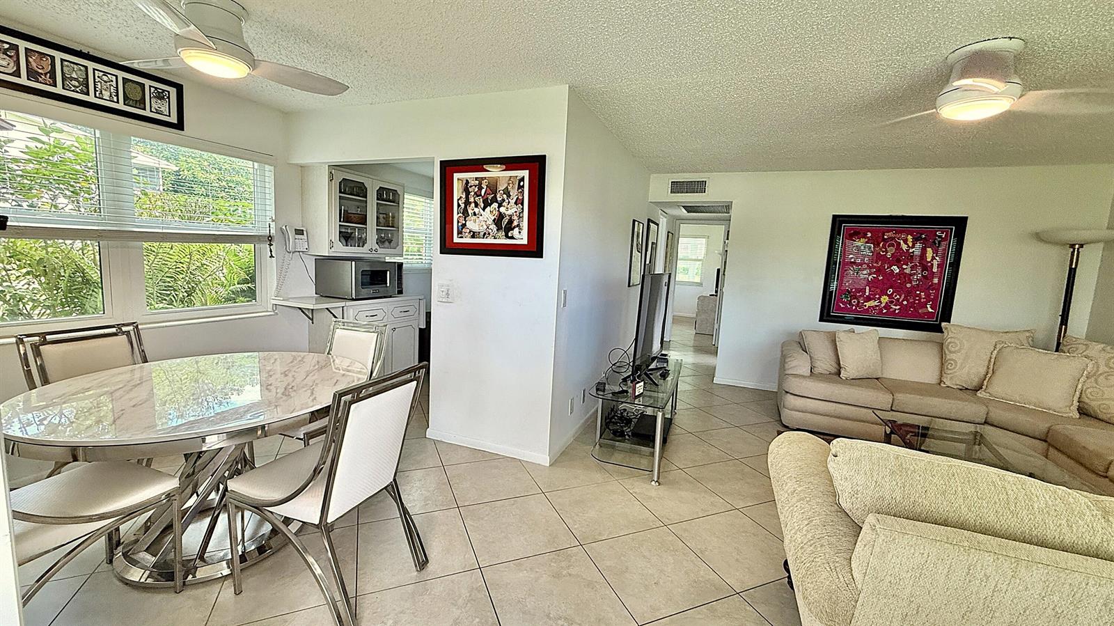 A dining area with a marble table and a living room with beige sofas — 316 Markham, Deerfield Beach FL 33442, DEERFIELD BEACH, FL