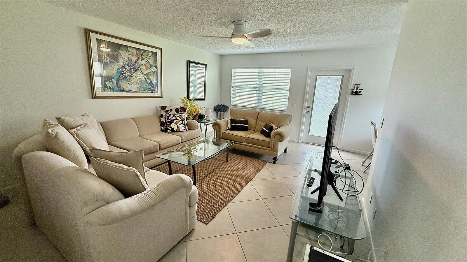 A living room features beige sofas, a glass coffee table, tile flooring, and a ceiling fan — 316 Markham, Deerfield Beach FL 33442, DEERFIELD BEACH, FL