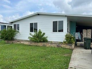 The exterior of a white single-story house features a brick foundation and a side carport — 263 MARINER DRIVE, NORTH PORT, FL