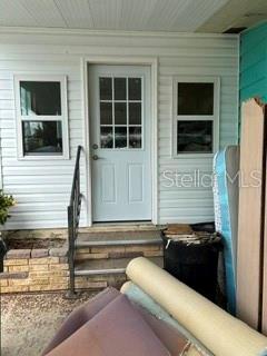 A white front door with a glass pane is flanked by two windows on a porch — 263 MARINER DRIVE, NORTH PORT, FL