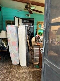 A cluttered room features a ceiling fan, two upright mattresses, and a wooden shelving unit — 263 MARINER DRIVE, NORTH PORT, FL