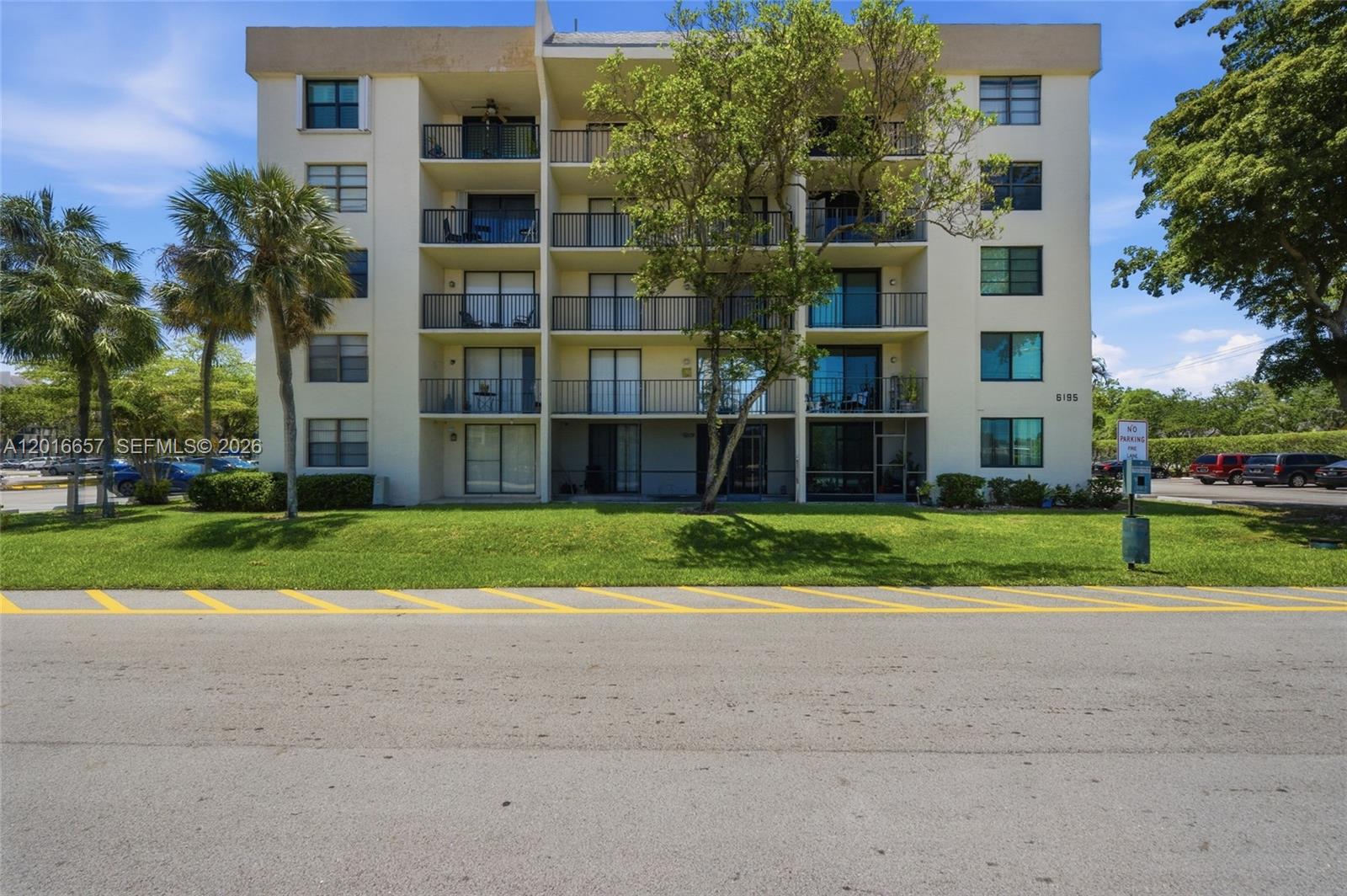 A multi-story apartment building features balconies, large windows, and a lawn with palm trees — 6195 Rock Island Rd # 511, Tamarac FL 33319, TAMARAC, FL