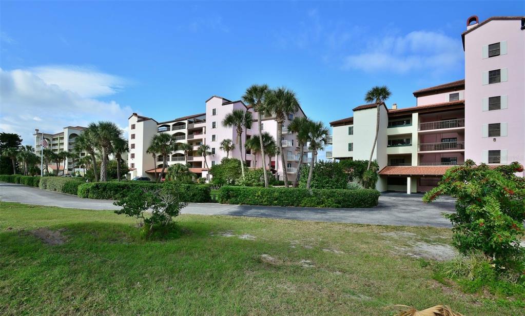 A multi-story pink apartment complex stands behind a grassy lawn and palm trees — 746 MARINA POINT DRIVE UNIT 7460, DAYTONA BEACH, FL