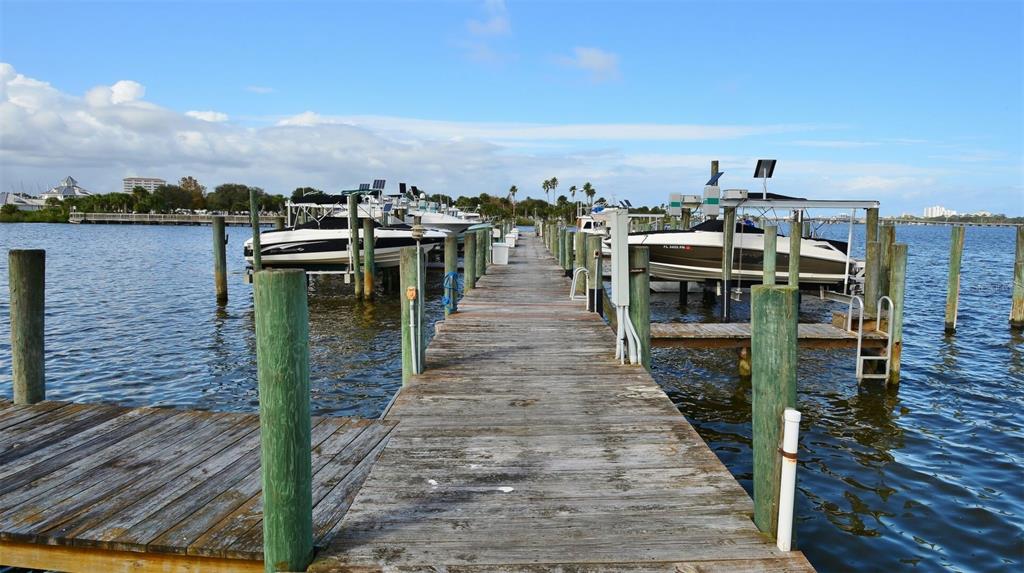 A wooden pier extends into a bay with boats docked in lifts on both sides — 746 MARINA POINT DRIVE UNIT 7460, DAYTONA BEACH, FL