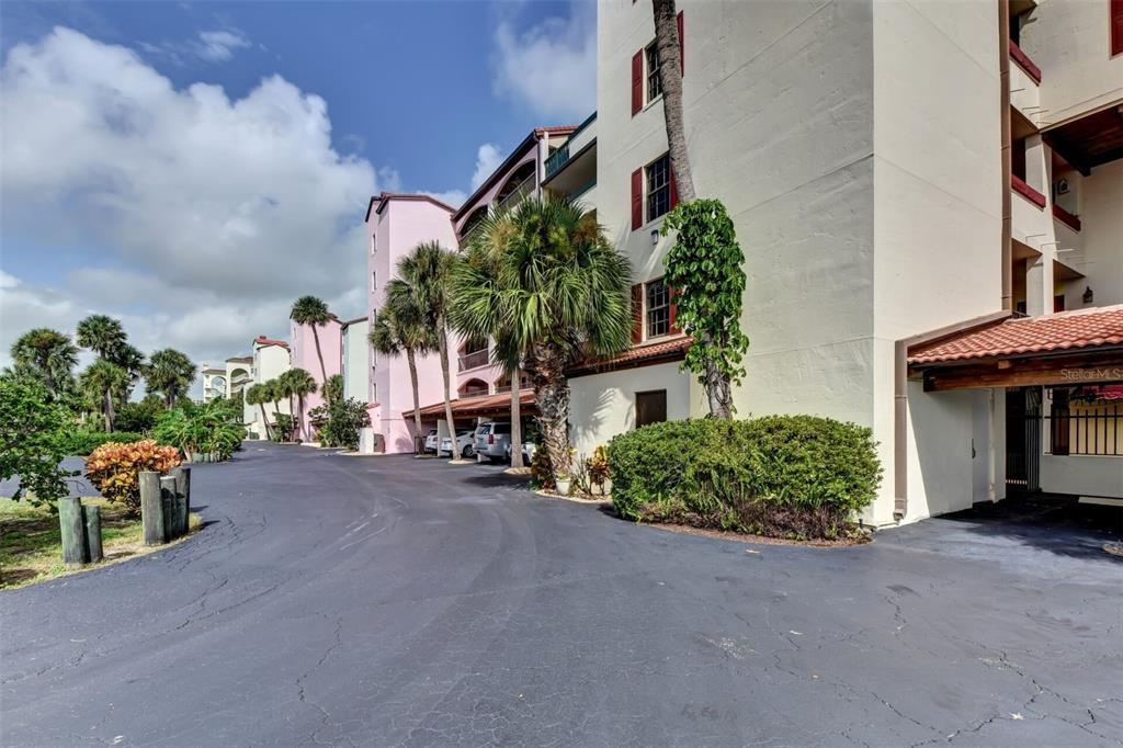 A multi-story apartment building with a paved driveway, palm trees, and covered parking — 746 MARINA POINT DRIVE UNIT 7460, DAYTONA BEACH, FL