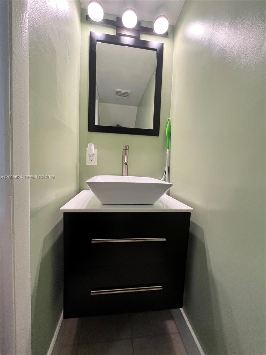A small bathroom features a floating black vanity with a white vessel sink and mirror — 5580 W 26th Ct # 204, Hialeah FL 33016, HIALEAH, FL