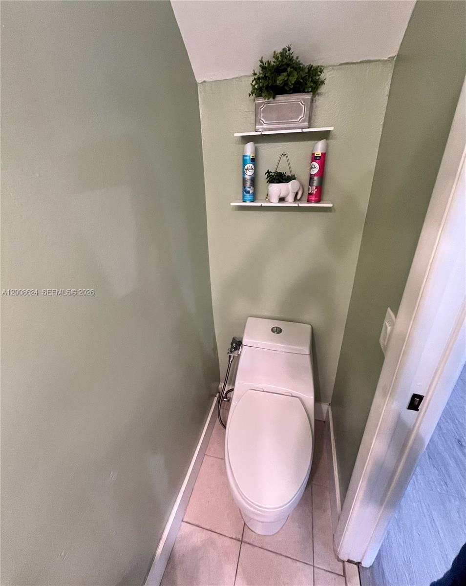 A toilet is positioned in a small alcove with two wall-mounted shelves above it — 5580 W 26th Ct # 204, Hialeah FL 33016, HIALEAH, FL